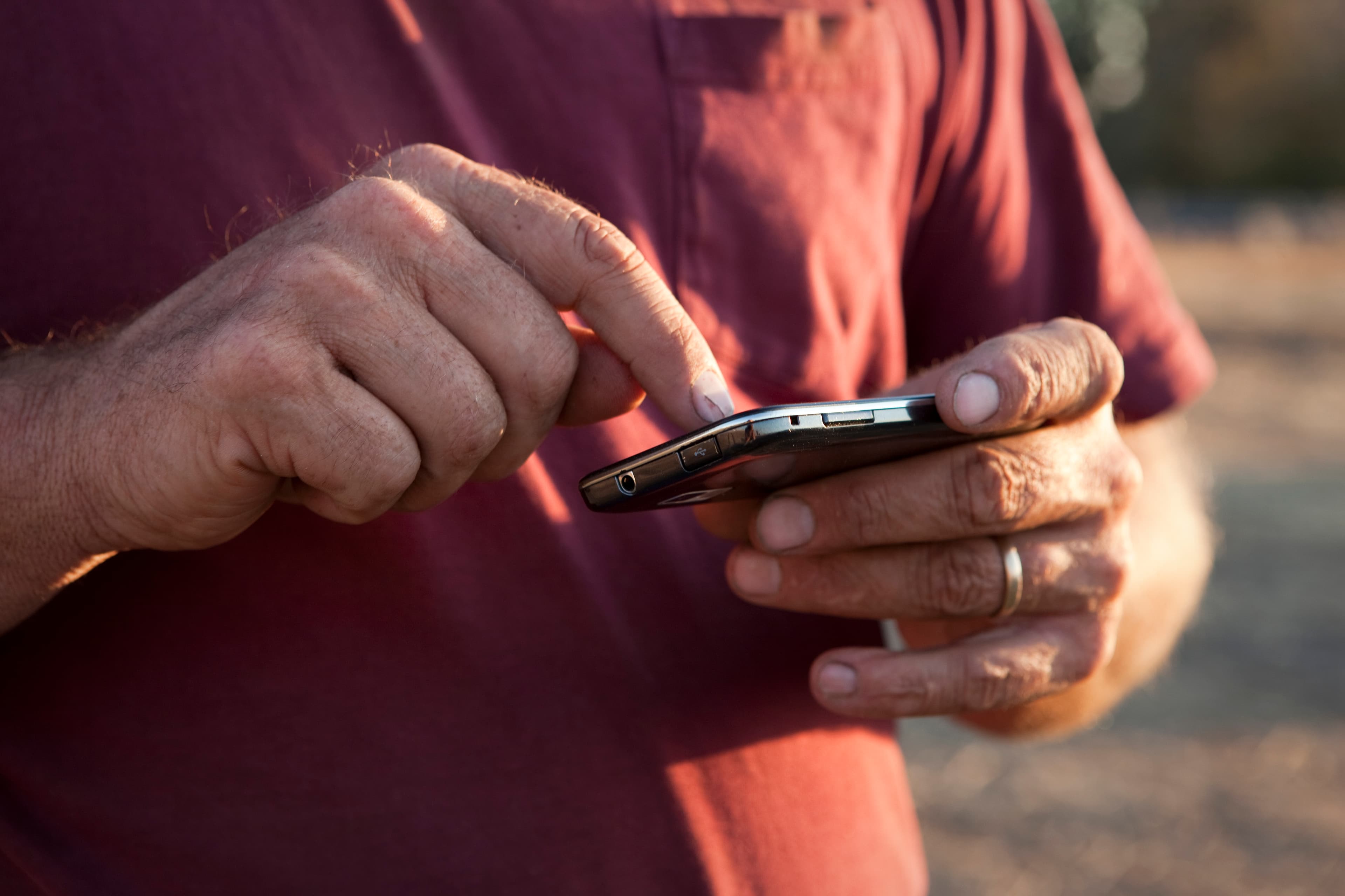 Nærbillede af en mand, der navigerer på sin smartphone, som repræsenterer enkelhed og digitale muligheder fra Uno-X.